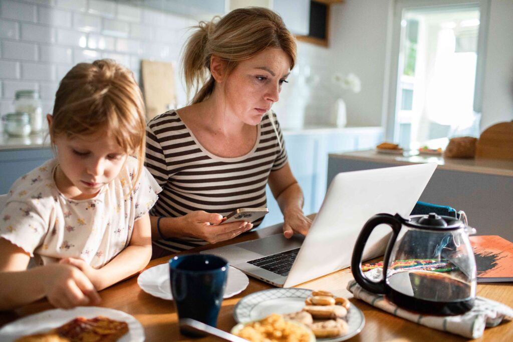 Mom working from home in kitchen with her child.